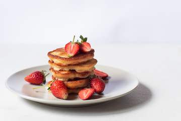 A stack of Russian pancakes with fresh strawberries on the light background 