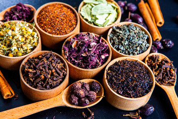 Various dried tea leaves in wooden bowl. Dried herbs tea leaves close up. Different dry herbs and flowers for making healthy tea background.