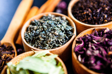 Various dried tea leaves in wooden bowl. Dried herbs tea leaves close up. Different dry herbs and flowers for making healthy tea background.