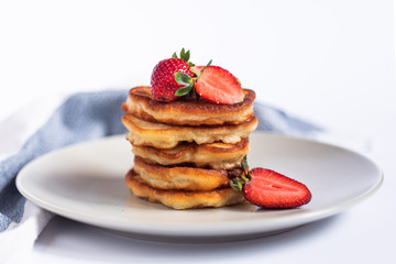 Russian traditional pancakes oladi with fresh strawberries. Towel on the background.