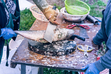 Vietnamese fishmongers using knife for fish skin brush scraping at Asian float market in Houston, Texas, USA