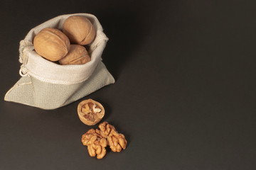 Walnuts scattered from a canvas bag on a black background. View from above. Place for text. Сopy space...