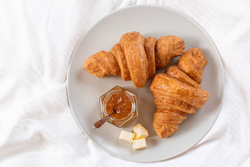 Two croissants in bed with marmalade and butter 