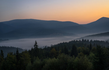 Plakat Smoky mountain landscape with mountain and light rays before sunrise.
