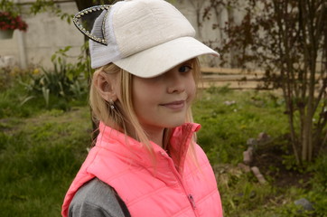 
Portrait of a beautiful girl in a pink vest and white baseball cap with ears.