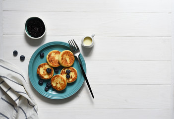 Cheese pancakes with jam and blueberries on the kitchen table. Good morning!