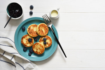Cheese pancakes with jam and blueberries on the kitchen table. Good morning!