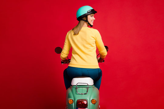 Rear back behind view of her she nice attractive cheerful cheery girl driving moped new purchase buying buyer owner transport isolated on bright vivid shine vibrant red color background