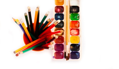 Naklejka premium Watercolor paint, brushes well used, pencils in holder on white background. Back to school, home schooling concept.