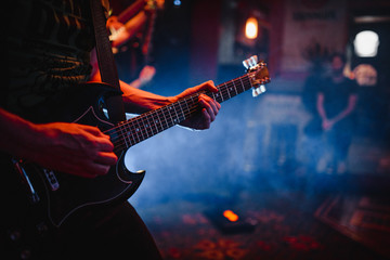 Silhouette of guitar player on stage. Dark background, smoke, spotlights.