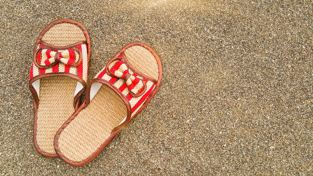 Straw beach sandals on the sand by the sea. Summer holidays. The beach background. Tourist holidays. Concept for the summer season. Flatlay foto. Copy space for text.