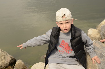 
Spring. River bank. The boy leaned on a large stone of gray granite.