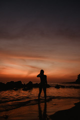 silhouette of a woman walking on the beach at sunset