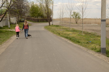 Family holiday. Mom and daughter walk a dachshund dog on the lake.