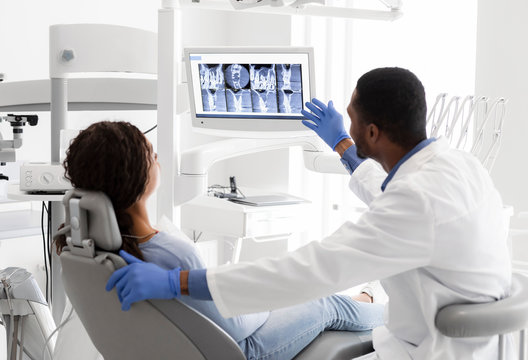 Dentist Explaining Xray On Screen To Female Patient