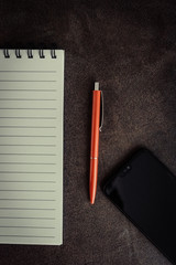 Notebook and pencil on brown background