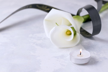 White flowers with a mourning ribbon on a concrete background. Copy space. Death concept
