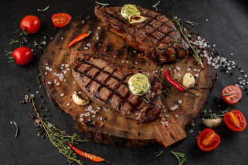 two large pieces of bone steak on wooden board next to sauce waiting for served ready.