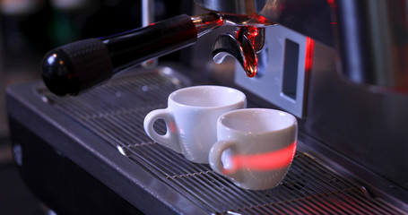 Two white espresso cups in a coffee machine.