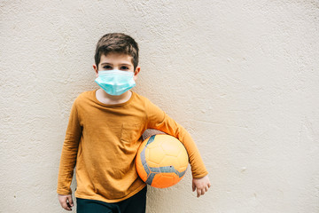 Little boy with a ball and protective mask.