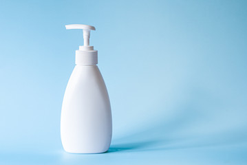 White bottle with dispenser for liquid soap on a turquoise background. Body care, beauty salon copyspace