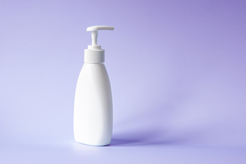 White bottle with dispenser for liquid soap on a lilac background. Body care, shower cosmetics, beauty salon copy space.