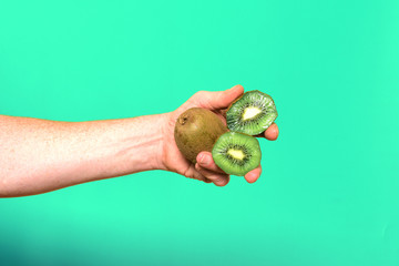 hand holding a group of kiwis on green background