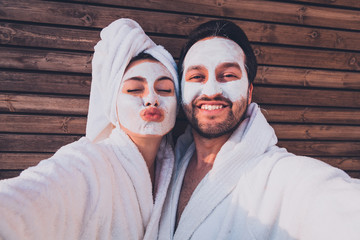 Close up selfie of beautiful happy couple after shower with a towel on head sending air kiss with...
