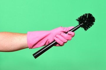 hand with glove hoding brush on green background