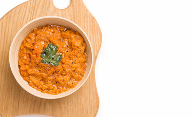 Dhal Indian cream bean soup on a wooden plank on a white background. Copy space.