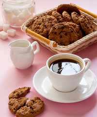 A Cup of coffee with crumbly oatmeal cookies on a pink background