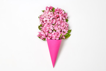 Blossom spring bouquet in ice cream cone. Pink bloom flowering, top view. Minimal creative concept. Springtime blooming background. Trendy pink vivid fashionable design.