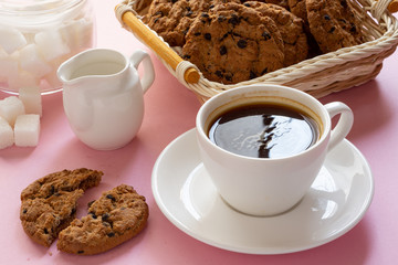 A Cup of coffee with crumbly oatmeal cookies on a pink background