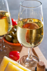 Glasses of dry fino sherry wine served with spanish tapas, manchego cheese, green olives, cheese crackers