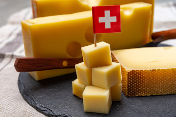 Swiss cheeses, block of medium-hard yellow cheese emmental or emmentaler with round holes and...