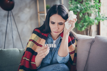Photo of pretty displeased lady stay home alone quarantine covered checkered blanket hold pills paper napkin coronavirus infection sitting comfortable sofa living room indoors
