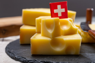 Block of Swiss medium-hard yellow cheese emmental or emmentaler with round holes and cheese knife
