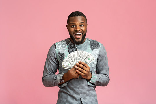 Happy black man in african shirt holding bunch of money