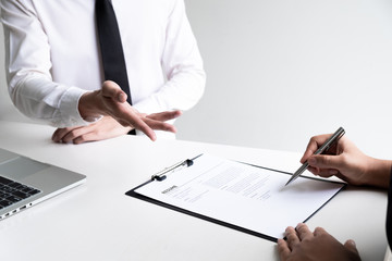 Interview employee is reading and checking a resume with a job applicant in the office.