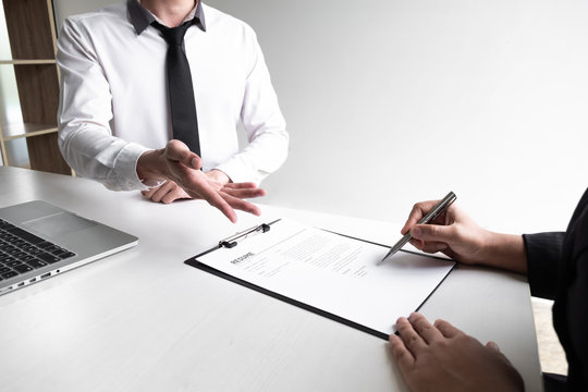 Interview employee is reading and checking a resume with a job applicant in the office.