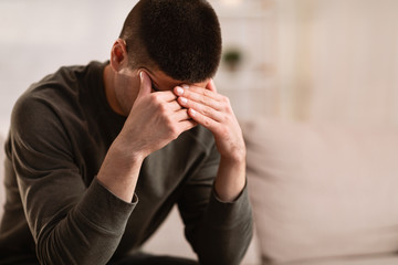 Obraz premium Ill man sitting on sofa with head on his hands