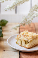 Kuchen mit Rhabarber und Streusel aus einem Blech auf einem Tisch aus hellem Holz