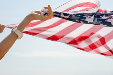  Young woman waving with american flag against blue sky