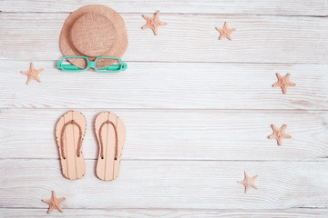 Concept of beach holiday. Beach flip-flops,  starfish, sunglasses, straw hat from sun. Summer flat lay with copy space. Summer wooden background. Minimal style.