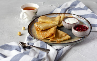 Folded thin crepes bliny served with rasberry jam and sour cream. Tasty breakfast concept