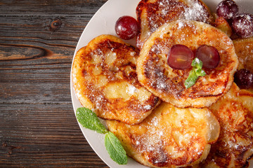 sweet homemade pancakes with powdered sugar, grapes and mint  on a wooden