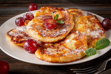 many sweet homemade pancakes with grapes , powdered sugar  and mint  on a wooden
