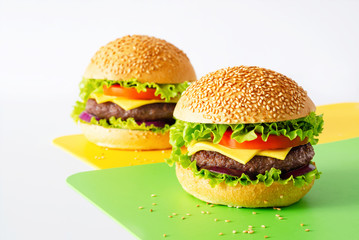 Two homemade burger on on the yellow and green napkins isolated on white background. Horizontal orientation.