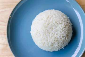 Cooked white jasmine rice on blue plate.