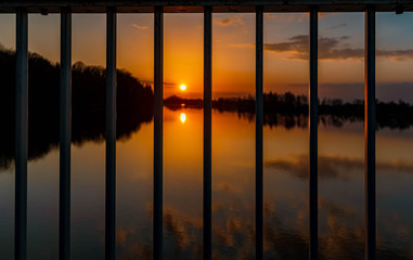 Beautiful sunset with reflections and details of a steel railing near Ettling, Isar, Bavaria, Germany